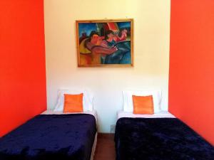 two beds in a room with a painting on the wall at Hostal Casa Vieja in Matagalpa