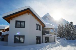 ein Haus im Schnee mit einem Berg im Hintergrund in der Unterkunft Zugspitzappartements in Ehrwald