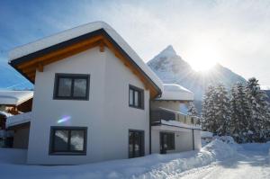 dom w śniegu z górą w tle w obiekcie Zugspitzappartements w mieście Ehrwald