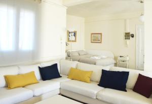 a white living room with yellow and blue pillows on a couch at Apartment with Rooftop Terrace & Acropolis View in Athens