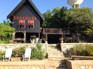 a black house with two white chairs and a staircase at Ayothaya Riverside House in Phra Nakhon Si Ayutthaya