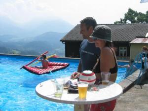 un hombre y una mujer de pie junto a una mesa en una piscina en Land- & Panoramagasthof Schöne Aussicht, en Viktorsberg