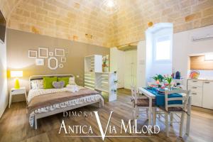 a bedroom with a bed and a table and a kitchen at Dimora Antica Via MiLord in Monopoli