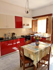 a kitchen with red cabinets and a table with chairs at Myrto's Apartment No15 in Loutra Oraias Elenis