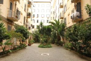 einen leeren Innenhof mit Palmen und Gebäuden in der Unterkunft Vertex Suite in Rom