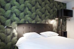 a bedroom with a large bed with a green wallpaper at Logis Hotel du Maine in Laval