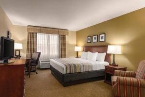 Habitación de hotel con cama, escritorio y TV. en Country Inn & Suites by Radisson, Dakota Dunes, SD, en Dakota Dunes