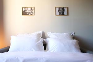 1 cama con almohadas blancas y una foto en la pared en StandingAppart Marmande Centre, en Marmande