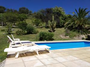 a pool with two white lounge chairs and a swimming pool at posada cerro los nogales in San Agustín de Valle Fértil