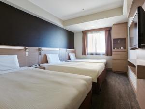 a hotel room with three beds and a television at Mitsui Garden Hotel Okayama in Okayama