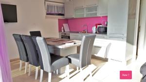 a kitchen with a table and chairs and pink walls at Apartment Villa Vala in Malinska