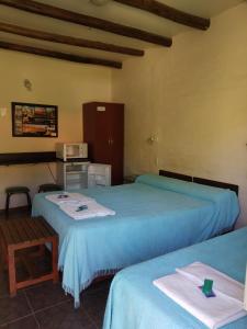Cette chambre comprend deux lits, une table et un four micro-ondes. dans l'établissement posada cerro los nogales, à Villa San Agustín