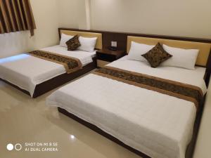 1 dormitorio con 2 camas con sábanas blancas en Ngọc Anh Hotel, en Ha Long