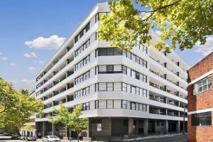 un gran edificio de apartamentos blanco en una calle de la ciudad en Ultimate 2-Bed Apartment in Surry Hills - Ultimate Convenience, en Sídney