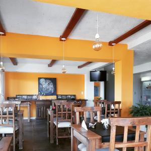 a restaurant with wooden tables and chairs and yellow walls at Punta Encanto Posada Boutique in Miramar