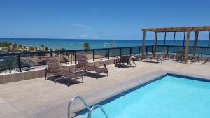 una piscina con sedie e vista sull'oceano di Flat Marinas - Cabo Branco - João Pessoa a João Pessoa