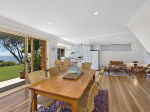 a living room with a wooden table and a kitchen at Stunning Ocean Views in Norah Head