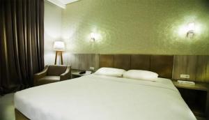 una habitación de hotel con una cama grande y una silla en Raden Wijaya Hotel & Convention, en Mojokerto