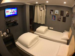 two beds in a room with a tv at Soso Hostel in Hong Kong