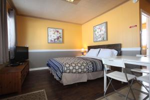 a hotel room with a bed and a desk and a television at Century II Motel in Fort Macleod