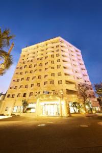 千葉的住宿－幕張法米酒店，一座白色的大建筑,前面有一棵棕榈树