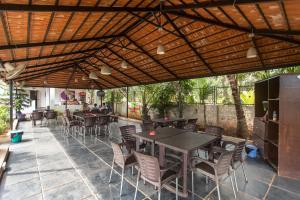 a patio with tables and chairs under a wooden roof at Moustache Goa Cowork Hostel in Mandrem