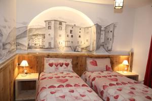 a bedroom with two beds and a mural of buildings at Al Papavero in Andalo