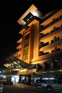 un edificio con coches aparcados delante de él por la noche en Hotel Kini Pontianak, en Pontianak