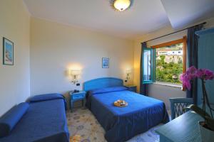 a blue bedroom with two beds and a window at Hotel La Pergola in Amalfi