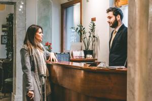 Un uomo e una donna in piedi davanti a un registratore di cassa. di Domus Florentiae Hotel a Firenze