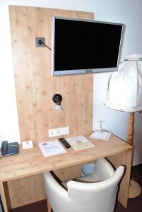 a desk with a television and a white chair at Landgasthof Goldener Pflug in Frasdorf