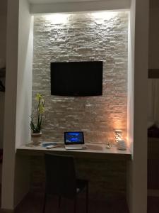 a desk with a laptop and a tv on a brick wall at A casa di Zia Caterina in Zambrone