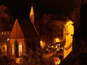 una calle de la ciudad por la noche con una iglesia y edificios en Ferienwohnung am Kirchplatz, en Lutherstadt Wittenberg