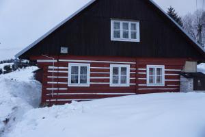 een rood huis met sneeuw ervoor bij Chata Azalka in Albrechtice v Jizerských horách