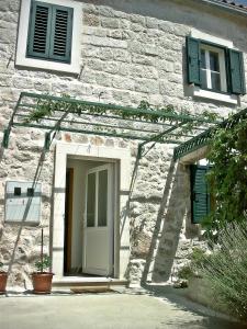 un edificio de piedra con puerta blanca y persianas verdes en Apartment Cukarin A2 BOL-CENTER, Croatia en Bol