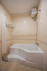 een badkamer met een wit bad en een douche bij Homesyn Hotel in Phnom Penh