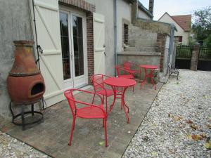 een groep rode tafels en stoelen op een patio bij Chez Denise in Champaubert