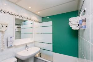 een badkamer met een witte wastafel en een groene muur bij Kyriad Nîmes Ouest A9 in Nîmes +37 foto's