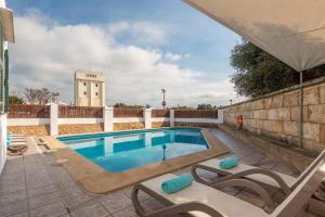 a swimming pool with lounge chairs next to a wall at Villa Menurka I in Cala en Blanes