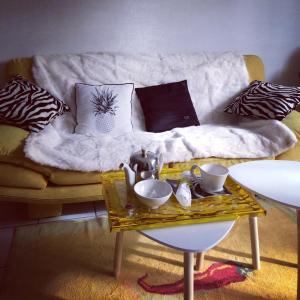 a living room with a couch with pillows and a table at Chambre d'hôtes THE YELLOW CUBE in Aubière
