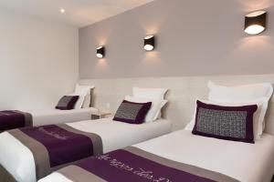 three beds in a room with white and purple at The Originals City, le Relais des Carnutes Brezolles Verneuil sur Avre in Brezolles