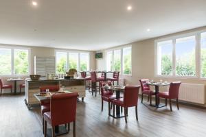a dining room with tables and chairs and windows at The Originals City, le Relais des Carnutes Dreux Ouest in Brezolles