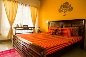 1 dormitorio con 1 cama grande con sábanas de color naranja y ventana en Siddhi Aloha, en Madikeri