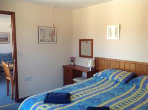 1 dormitorio con cama, escritorio y espejo en Stable Cottages, en Cowes