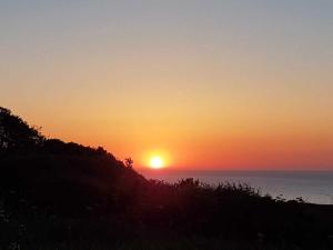 a sunset over the ocean with the sun in the sky at Gaestehaus Cap Hoorn in Helgoland