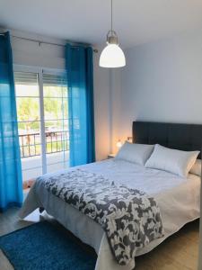 1 dormitorio con 1 cama con cortinas azules y ventana en El Toyo - Cabo de Gata, en Almería
