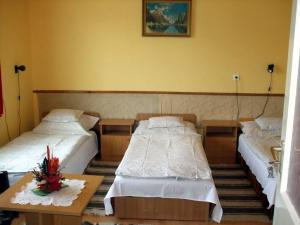 a room with two beds and a table with flowers at Lugas Szallas in Jászberény