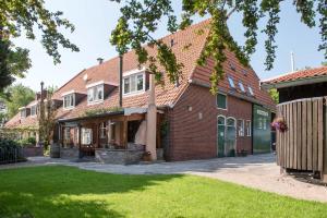 een oud bakstenen huis met een rood dak bij Hotel De Nieuwe Tijd Wieringermeer in Slootdorp