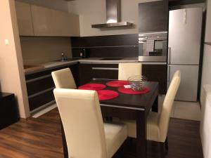 uma cozinha com uma mesa preta e cadeiras brancas em Apartamenty Tychy Bielska 145 em Tychy
