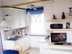 a kitchen with white cabinets and a computer on a desk at Bungalow Ungers Welt 1 in Ostseebad Nienhagen